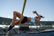 © Trevor Adeline/Caia Image - Female track and field athlete high jumping over pole
