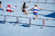 © Trevor Adeline/Caia Image - Female track and field athletes jumping hurdles on sunny track