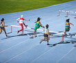 © Trevor Adeline/Caia Image - Female track and field athletes jumping hurdles in competition