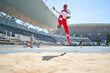 © Trevor Adeline/Caia Image - Female track and field athlete long jumping over sand in sunny stadium