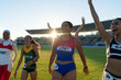 © Trevor Adeline/Caia Image - Happy female track and field athletes celebrating in sunny stadium