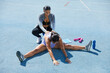 © Trevor Adeline/Caia Image - Trainer helping female track and female athlete stretch on track