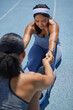 © Trevor Adeline/Caia Image - Female track and field athletes stretching on sunny track