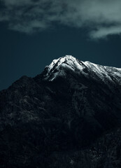 Wall Mural - Vertical shot of a rocky mountain covered with snow under a cloudy sky