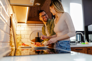 Romantic couple is cooking on kitchen. Young couple spending time in kitchen, making a pasta.