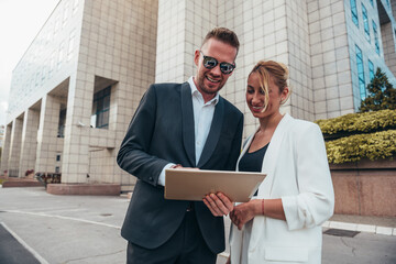 Wall Mural - Two businesspeople using a tablet while having a meeting outside