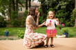 © Tetra Images - Mother and toddler daughter blowing bubbles in garden