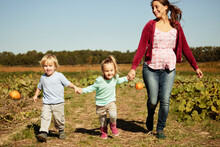 Mother With Two Children Running In Pumpkin Field