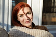 © Tetra Images - Portrait of young woman with red hair on porch