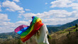 © OksanaFedorchuk - Blonde, lesbian, woman holding a rainbow LGBT gender identity flag on sky background with clouds on a sunny day and celebrating a gay parade