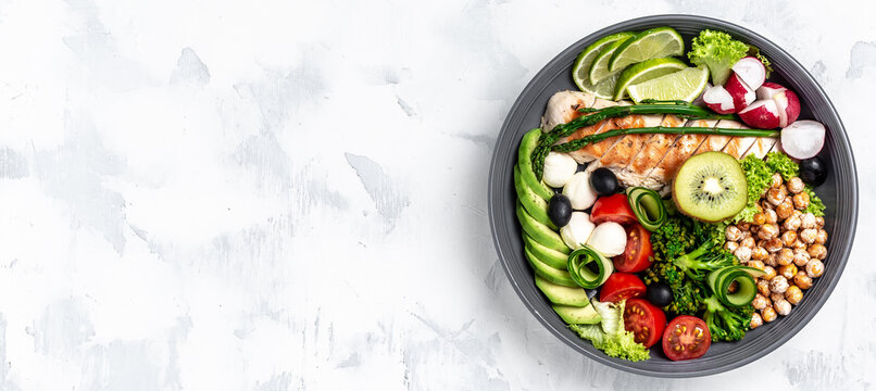 Buddha bowl dish with chicken fillet, asparagus, chickpeas, broccoli, radish, cucumber, avocado, tomatoes, mozzarella. Detox and healthy superfoods bowl concept, top view, flat lay