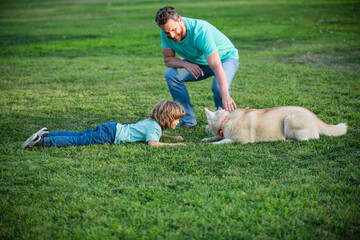 Wall Mural - Father and son playing with dog in park. Dad and child having fun outdoors.