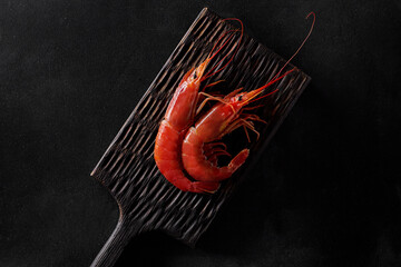 Top view of two whole boiled prawns on wooden board