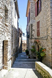 Fototapeta Przestrzenne - A street between old medieval stone buildings of Bassiano, historic town in Lazio region, Italy.