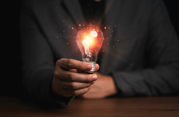 Businessman holding light bulb with orange rays , creative thinking idea and innovation concept.