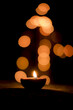 Glowing candle in a dark room with orange bokeh lights background