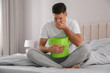 © New Africa - Man with bucket suffering from nausea on bed at home. Food poisoning