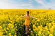 © artifirsov - Attractive woman in blooming rapeseed field with sunset light. Yellow flowers and happy woman