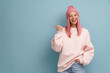 © Drobot Dean - Young woman wearing pink hat laughing and pointing finger aside
