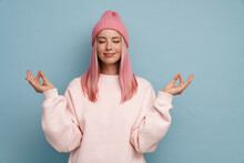 Young Woman Wearing Pink Hat Smiling And Making Meditation Gesture