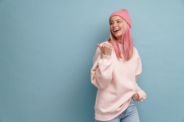 Wall Mural - Young woman wearing pink hat laughing and pointing finger aside