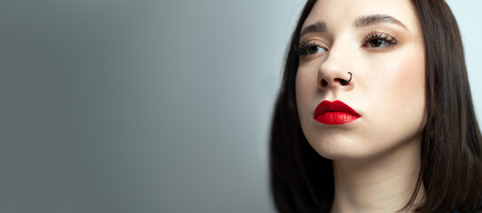 Wall Mural - Portrait of a young beautiful brunette with piercings in her nose. On an isolated background