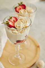 Sticker - Delicious cream dessert with coconut truffles and strawberries on a wooden round serving board