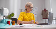 © TommyStockProject - Senior mature elegant female fashion designer drawing sketches in studio office.