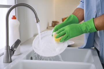 Wall Mural - Man washing plate above sink in kitchen, closeup