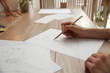 Young woman drawing male portrait at table indoors, closeup