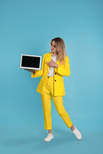 Young Woman With Modern Laptop On Light Blue Background