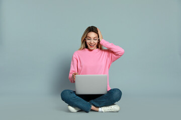 Wall Mural - Young woman with modern laptop on grey background