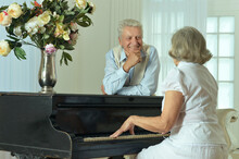 Senior Woman Playing The Piano At Home With Her Husband