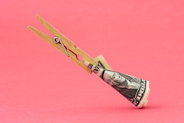 Wall Mural - Clothespin with one dollar over pink background