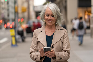 Poster - Mature caucasian woman in city walking street using cellhpone