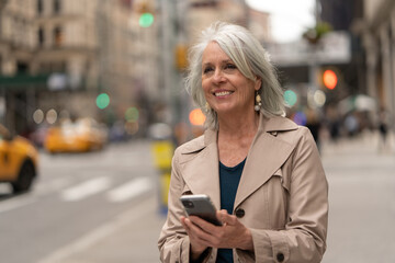 Poster - Mature caucasian woman in city walking street using cellhpone