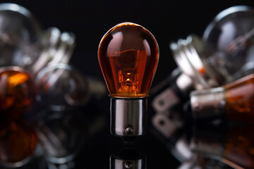 Orange car light bulb against blurred lamps on dark background, small depth of focus. Automotive parts.