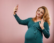 young pregnant woman is talking by video call on smartphone