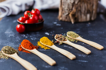 spoons with spices, paprika, basilic, pepper, thyme with cherry tomatoes