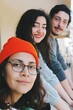 three young friends of turkish ethnicity in height order looking at camera smiling at outdoors home balcony