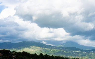 Wall Mural - Stunning landscape with green hills and mountains during a cloudy day.