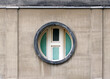 Round porthole window. The toilet window is painted green. The facade of a modernist building.