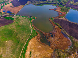 Aerial view of a lake in a rural enviroment photographed from a drone at a high altitude and a higher angle. Drone shot of a lake with reed and bullrush.