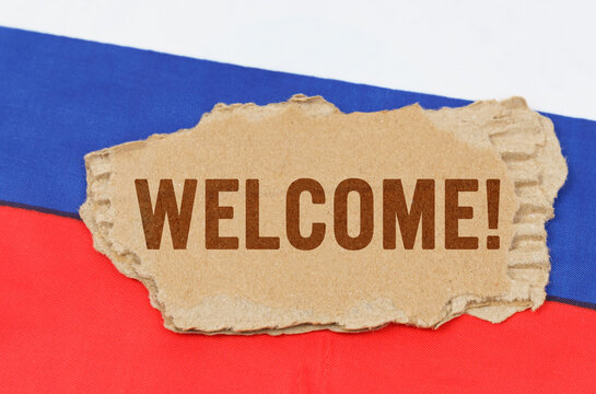 Against the background of the Russian flag lies cardboard with the inscription - Welcome