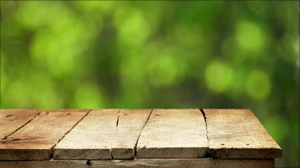 Wall Mural - Empty wooden table background with fresh green defocused background