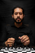 © Narayan - latin man with beard playing chess making decisions, chess concept