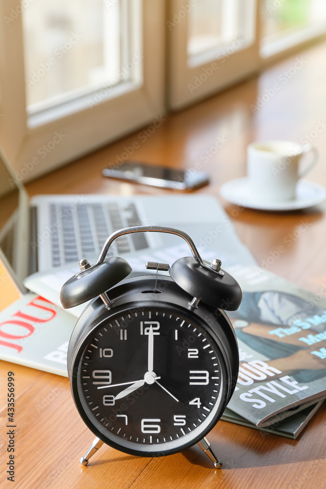 Alarm clock and magazines on windowsill in room