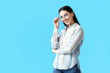 Wall Mural - Beautiful young woman wearing eyeglasses on color background