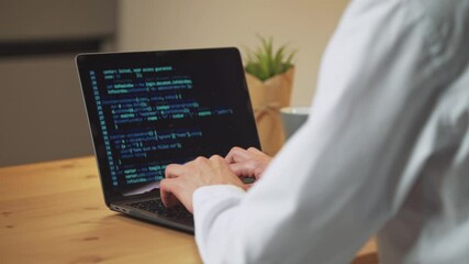 male programmer is working on creating software, typing program code on a laptop keyboard, programme