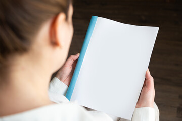 Wall Mural - top view of a woman reading an open book or magazine. empty page. mock up